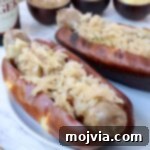 Grilled bratwurst in a bun topped with sauerkraut on a plate, ready to eat.