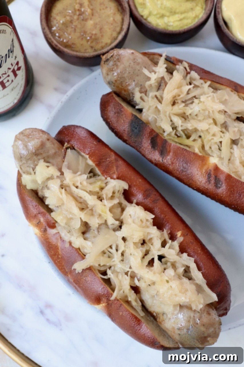 A golden grilled bratwurst perfectly placed in a toasted pretzel bun, generously topped with warm sauerkraut, all served on a rustic plate.