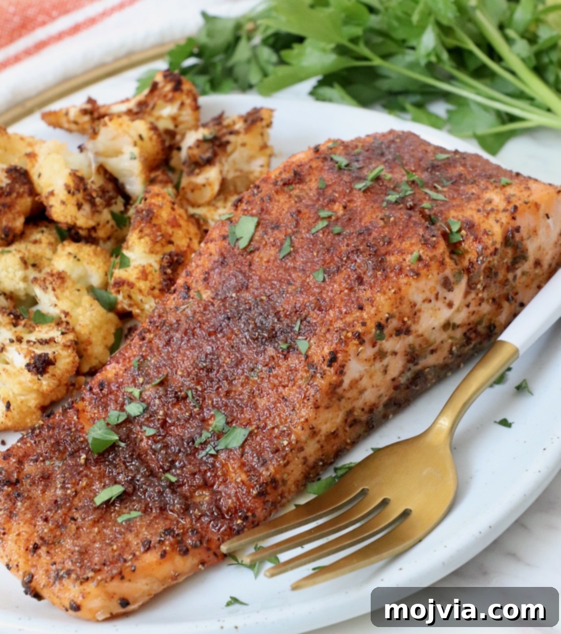 Golden Roasted Cauliflower 5 A perfectly cooked salmon fillet served alongside a generous portion of crispy roasted cauliflower on a white plate, ready for a healthy meal.