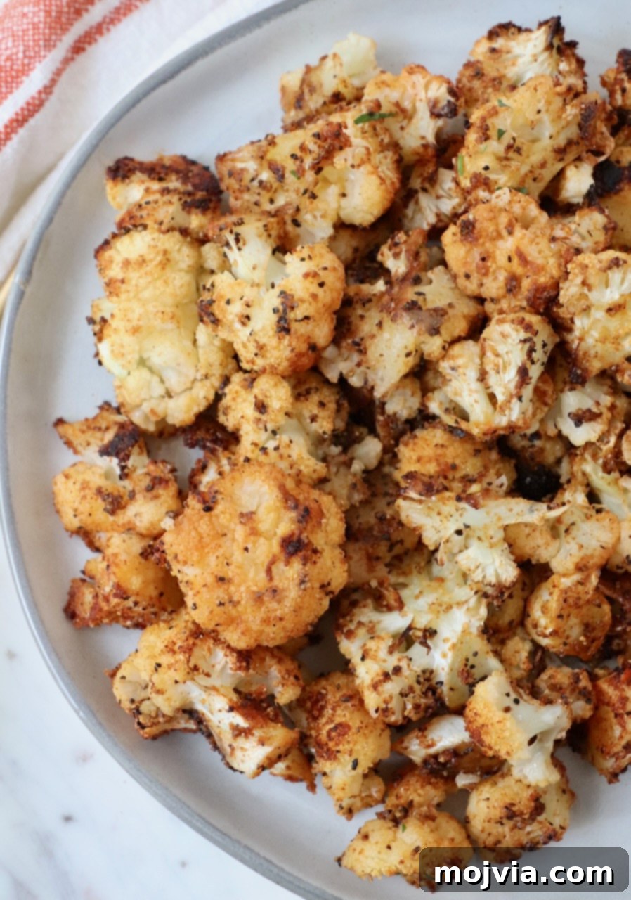 Golden Roasted Cauliflower 6 A generous serving of crispy roasted seasoned cauliflower, golden brown and delicious, presented on a white plate.