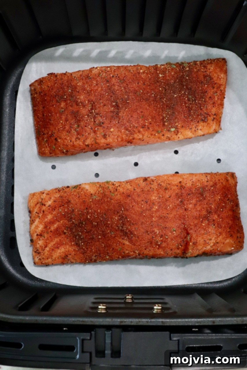 Crispy Air Fryer Salmon 5 Seasoned salmon fillets arranged in an air fryer basket, ready for cooking.