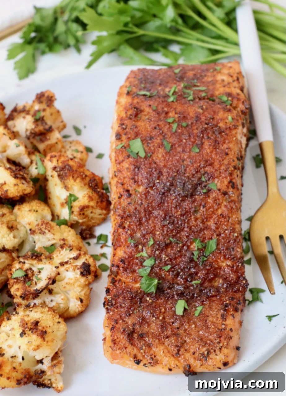 Crispy Air Fryer Salmon 6 Air fryer salmon served on a plate with roasted cauliflower, showing its flaky texture and golden-brown seasoning.