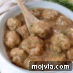 meatballs in gravy in a bowl with a spoon