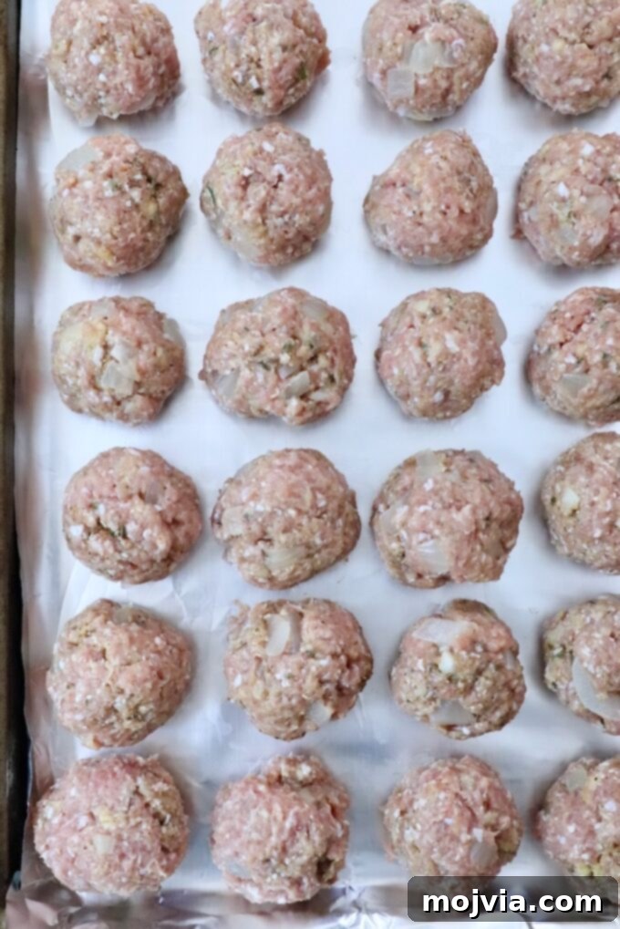 uncooked turkey meatballs on a foil lined baking sheet