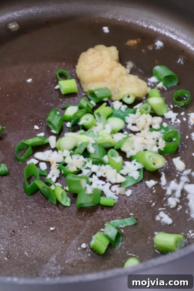 Comforting Gyoza Dumpling Soup 5 Finely diced green onions, minced garlic, and ginger paste sizzling in a pot, releasing their aromatic flavors.