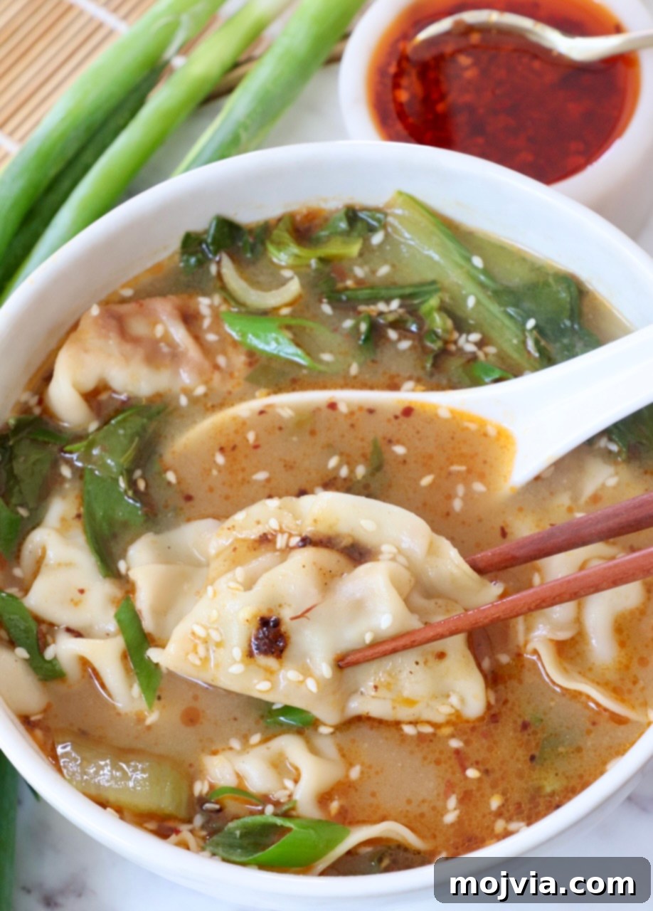 Comforting Gyoza Dumpling Soup 8 A bowl of Gyoza Soup with chopsticks resting on the side and a spoon inside, showcasing the delicious meal ready to be eaten.
