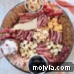 A beautifully arranged Fall Charcuterie Board featuring cured meats, an assortment of cheeses, vibrant seasonal fruits, and various crackers.