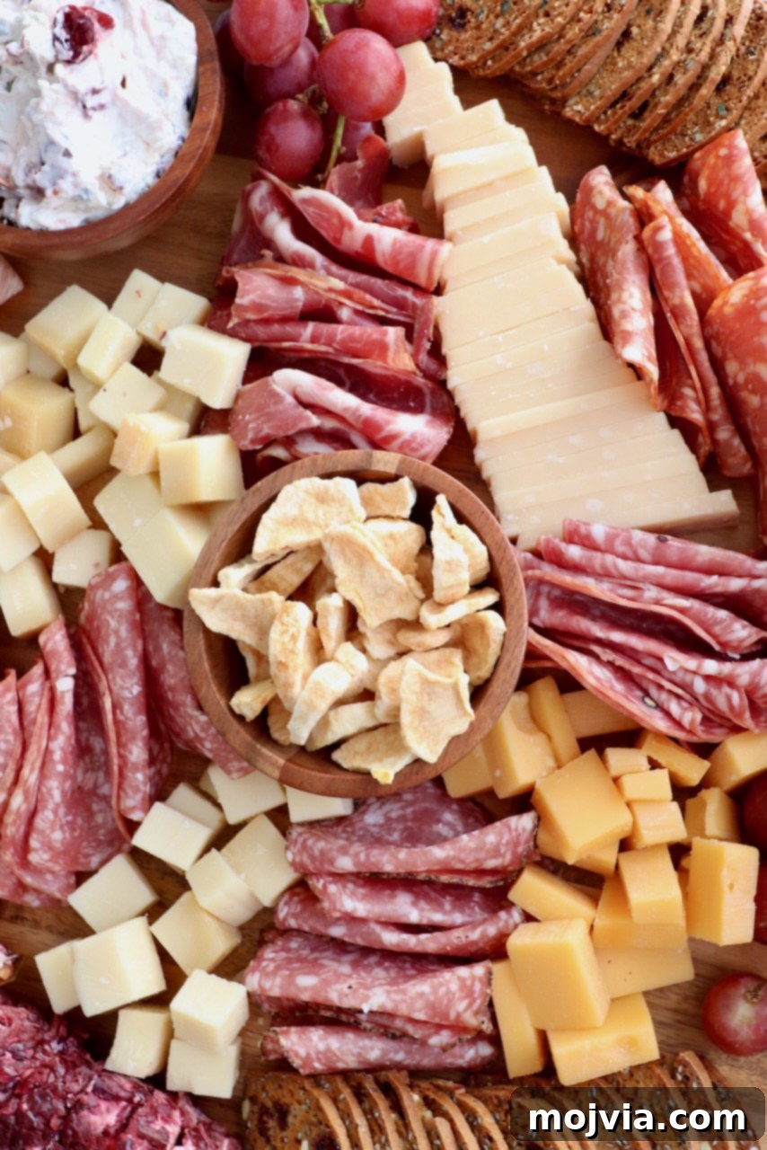 Autumn's Bounty Board 5 A close-up view of a bountiful Fall Charcuterie Board, showcasing an intricate arrangement of various cured meats, gourmet cheeses, a medley of fresh and dried fruits, and an assortment of crackers, all ready for serving.