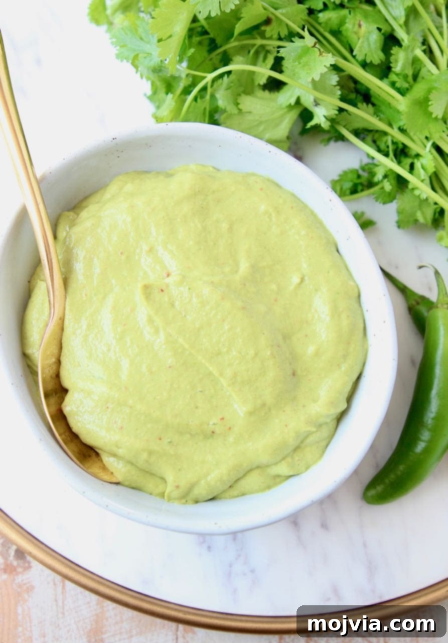 Creamy avocado sauce in bowl with gold spoon