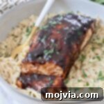 balsamic glazed salmon in a bowl with cooked orzo and a fork