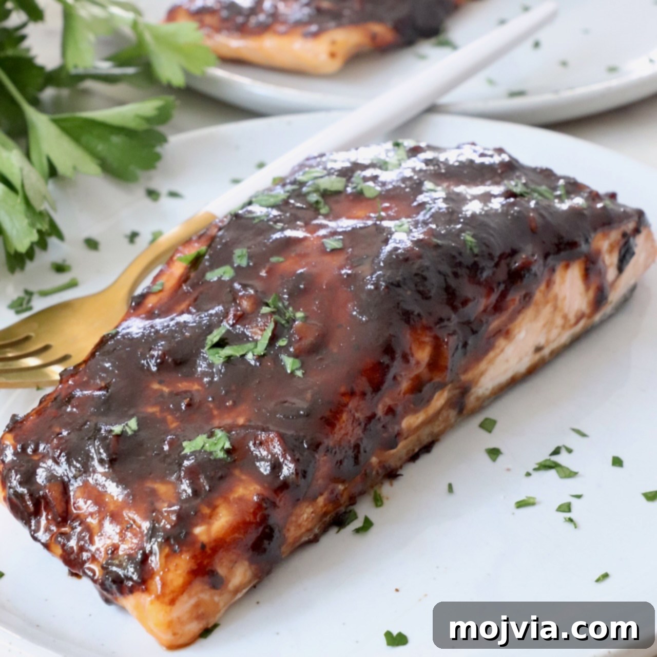 Sticky Balsamic Glazed Salmon 6 Balsamic glazed salmon on a plate with a fork, ready to be eaten, showing the perfectly cooked fish and shiny glaze.