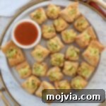 Dill Pickle Pastry Poppers 8 puff pastry pickles bites on a plate with a small bowl of hot sauce