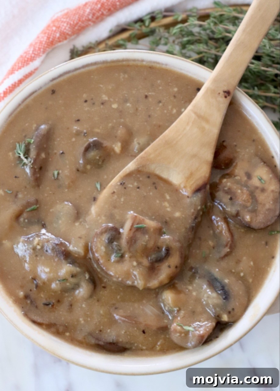 Wild Mushroom Gravy 2 Rich, creamy mushroom gravy in a bowl with a spoon, perfectly textured and ready to be served over various dishes.