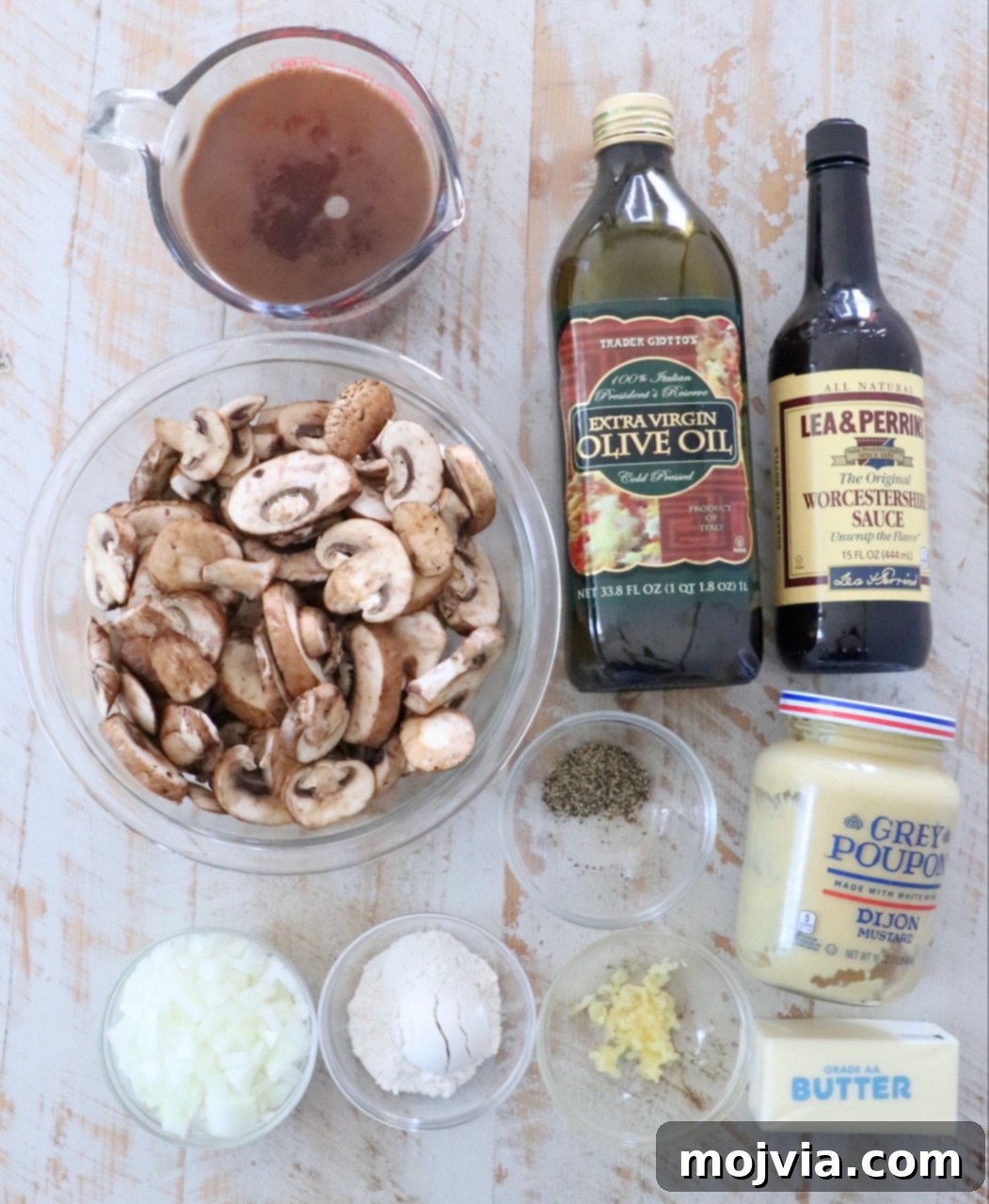Wild Mushroom Gravy 3 Various fresh ingredients for homemade mushroom gravy are neatly arranged on a white wooden board, highlighting the quality of the components.