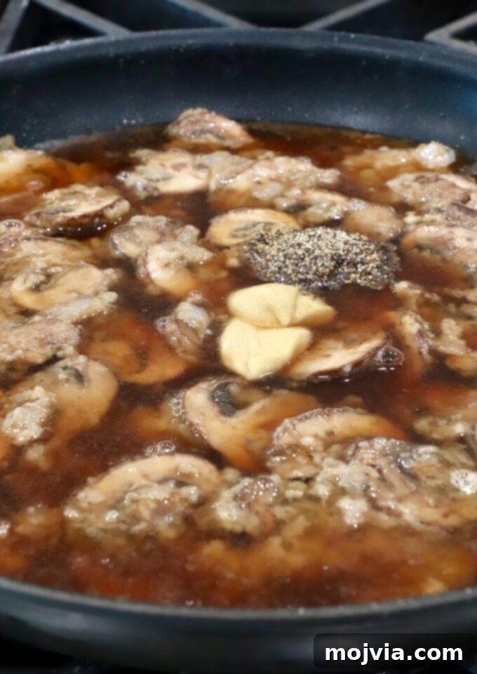 Wild Mushroom Gravy 8 Beef broth, Dijon mustard, and black pepper added to the skillet with the mushroom roux, ready to simmer.