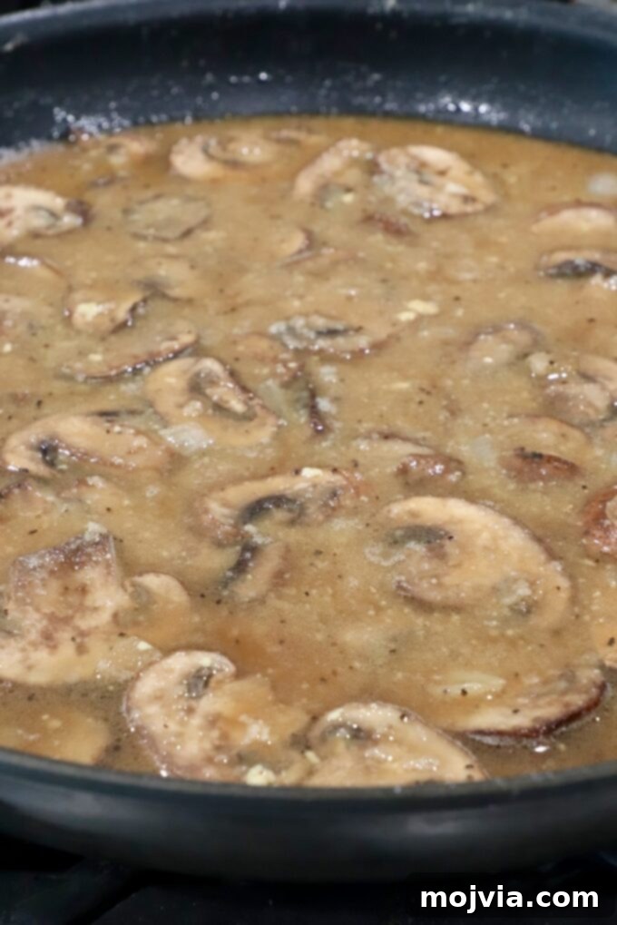 Wild Mushroom Gravy 9 The rich, creamy mushroom gravy simmering in a large skillet, reaching its perfect consistency.