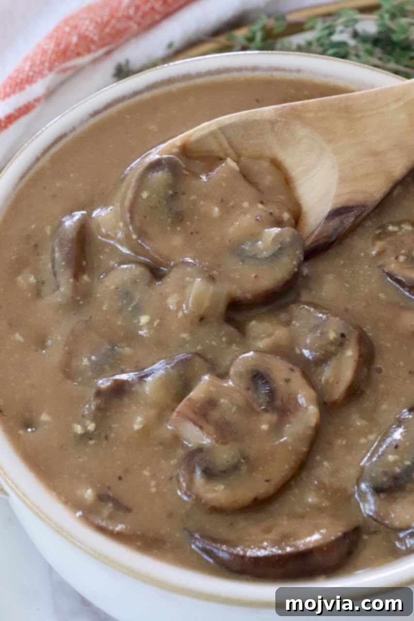 Wild Mushroom Gravy 10 A bowl of freshly made, creamy mushroom gravy with a spoon, highlighting its inviting texture and rich color.