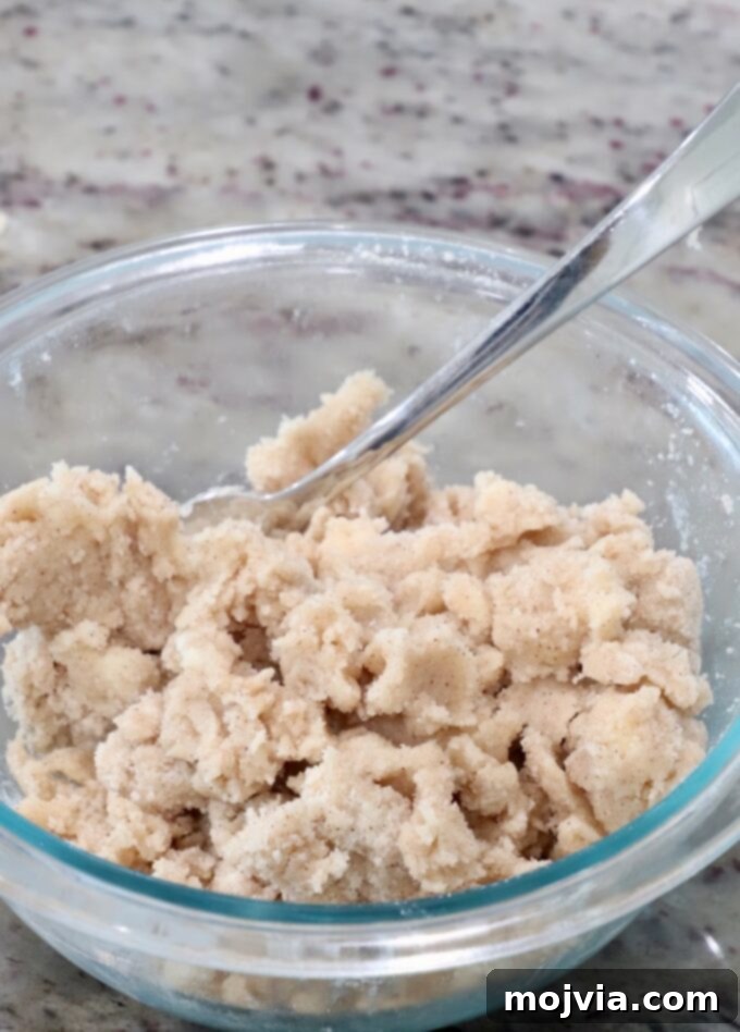 Cinnamon sugar crumble mixture in a glass bowl, showing its coarse, textured consistency before being spread.