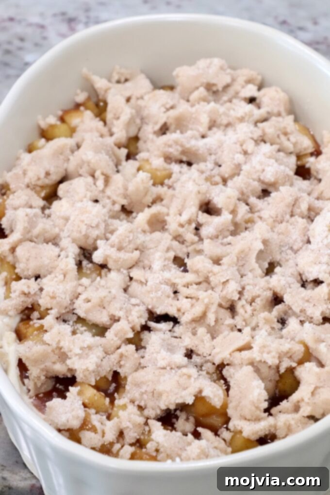 The cinnamon sugar crumble evenly distributed over the apple pie filling in a casserole dish, ready for baking.