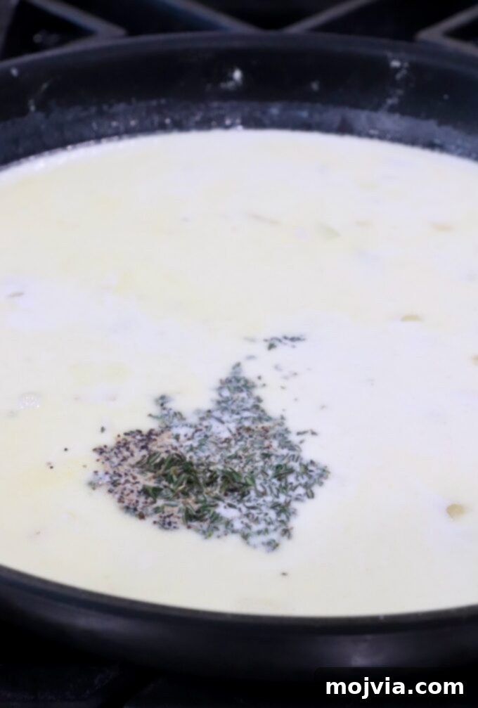 Ultimate Cheesy Potato Bake 7 creamy sauce in a skillet with dried herbs and spices