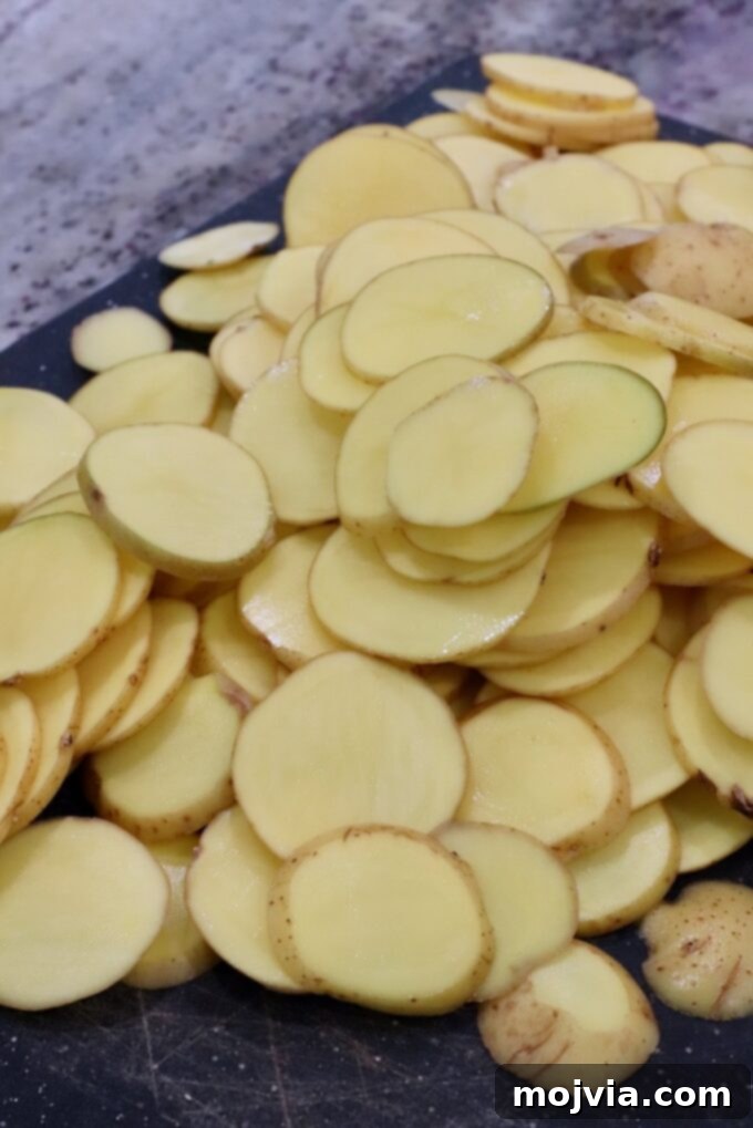 Ultimate Cheesy Potato Bake 8 thinly sliced gold potatoes on cutting board