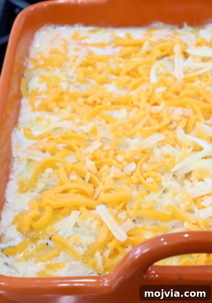 Ultimate Cheesy Potato Bake 9 layered creamy potatoes in a baking dish topped with shredded cheese