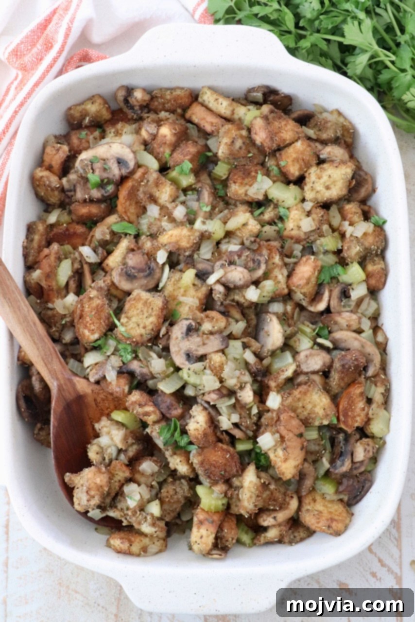Umami Mushroom Stuffing 2 Classic mushroom stuffing in a ceramic casserole dish, ready to be served, with a serving spoon.