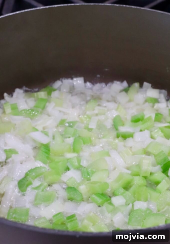 Umami Mushroom Stuffing 5 Diced onions and celery beginning to soften in melted butter within a large pot on the stovetop.