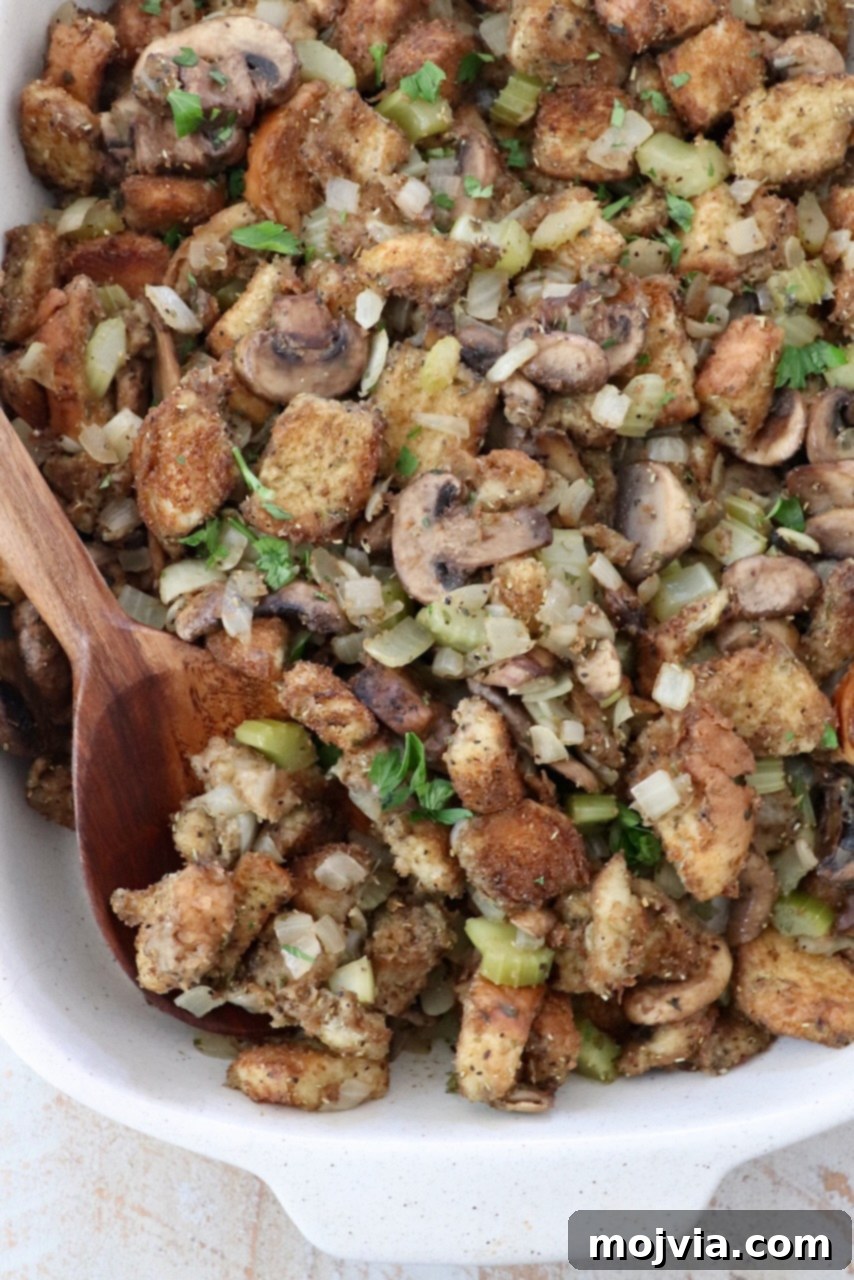 Umami Mushroom Stuffing 10 A rich mushroom stuffing baked to golden perfection in a casserole dish, garnished with fresh herbs and a serving spoon, highlighting its comforting appeal.