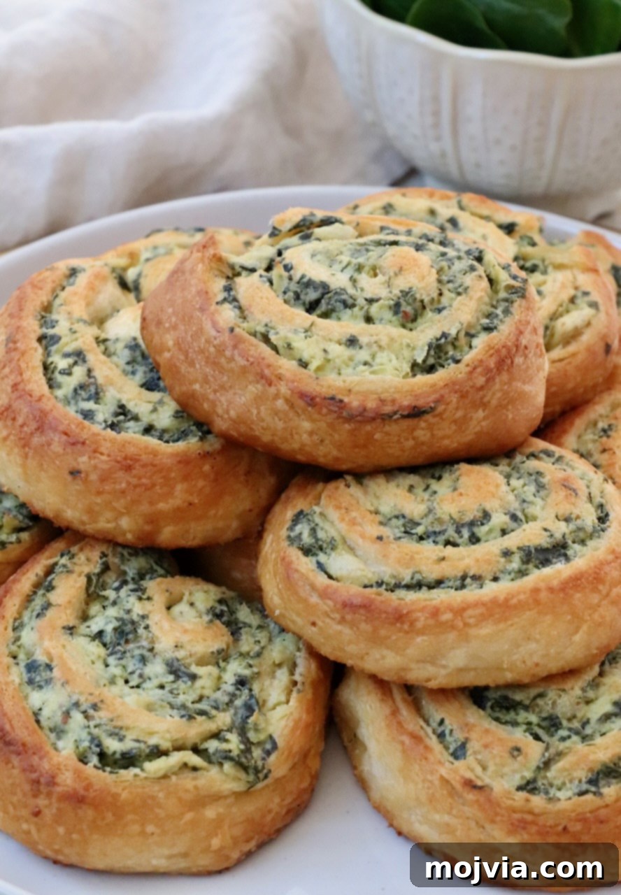 Savory Spinach Swirls 9 More spinach rolls stacked on a plate, highlighting their appetizing appearance for serving