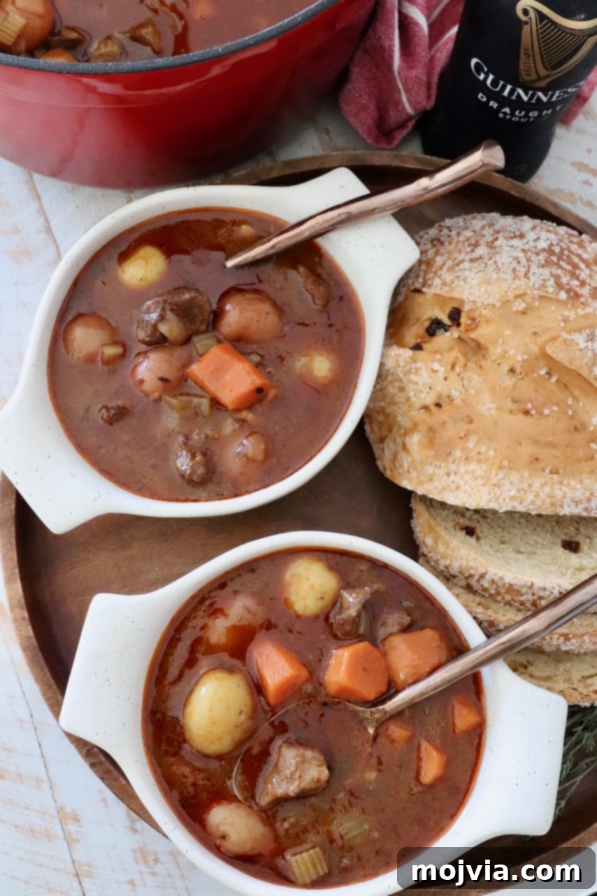Two bowls of Irish stew with spoons, served alongside sliced bread for dipping