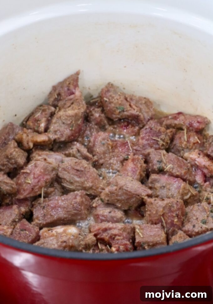 Perfectly seared, seasoned, cubed beef in a large Dutch oven