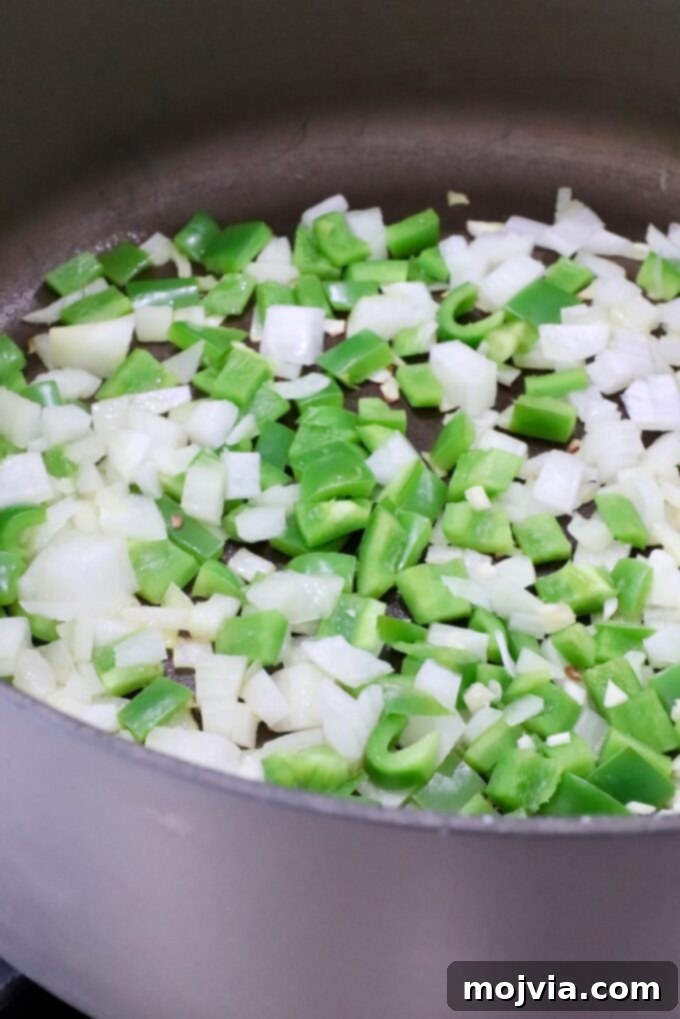 Diced onions and green bell peppers sautéing in olive oil in a large Dutch oven.