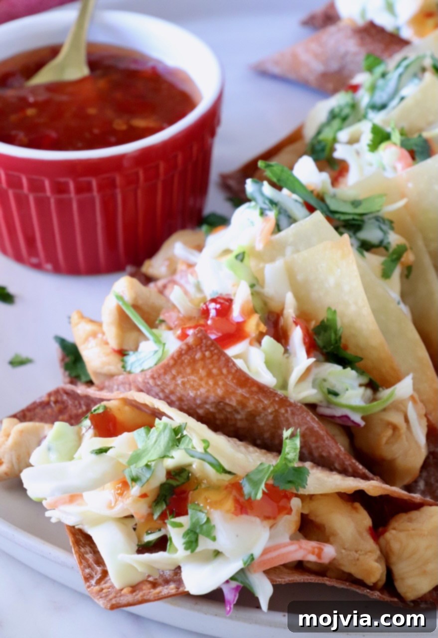 Asian Chicken Wonton Tacos 2 Delicious chicken wonton tacos, lined up and ready to serve, with a side of sweet chili dipping sauce