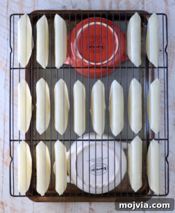 Asian Chicken Wonton Tacos 6 Wonton wrappers carefully draped over a wire rack, supported by two bowls on a baking sheet, ready for baking
