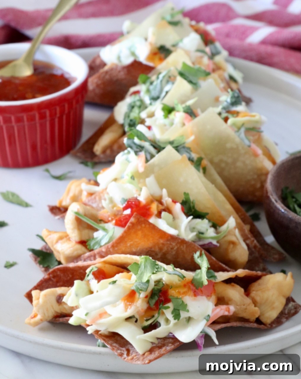 Asian Chicken Wonton Tacos 9 Finished chicken wonton tacos, garnished with fresh cilantro and a drizzle of sweet chili sauce, elegantly presented on a plate