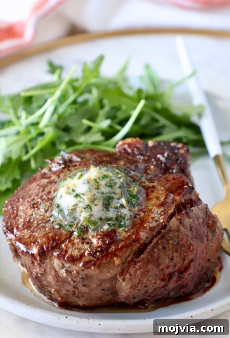 Butter Infusions 7 cooked steak on a plate topped with herb butter with arugula on the side of the plate