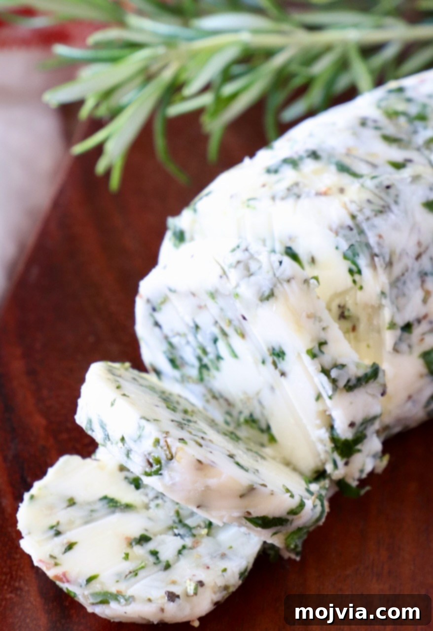 Butter Infusions 9 sliced herb butter on a wood cutting board with fresh rosemary