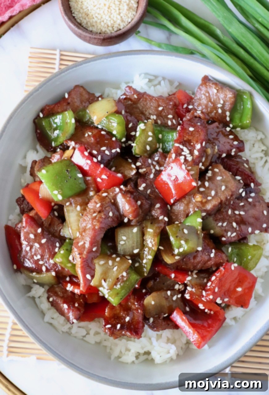 prepared pepper steak on top of cooked white rice in a bowl