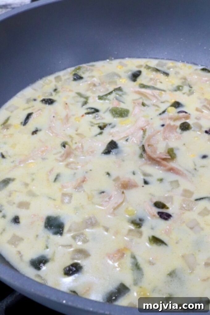 Roasted Poblano Chicken Soup 11 The finished creamy chicken poblano soup stirred and ready to serve in a large pot.