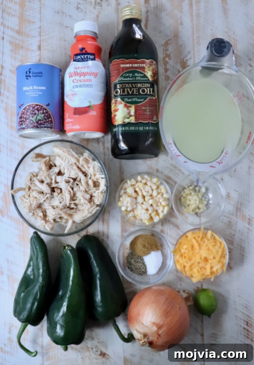 Roasted Poblano Chicken Soup 3 A vibrant display of fresh ingredients for Chicken Poblano Soup laid out on a white wooden board, including poblano peppers, corn, black beans, onions, garlic, and shredded chicken.