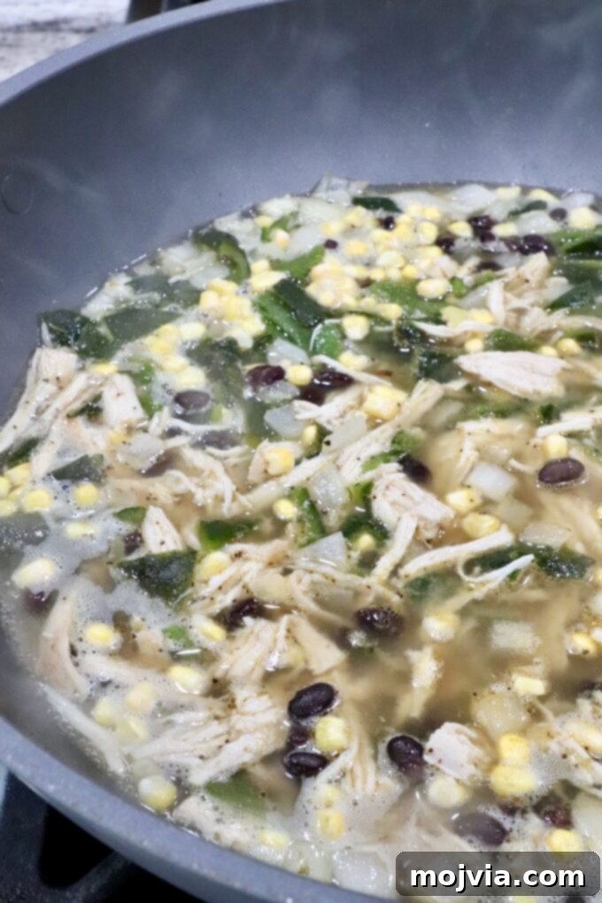 Roasted Poblano Chicken Soup 9 Chicken poblano soup simmering in a large pot on the stove, with all ingredients combined.