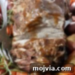 roasted pork on a serving platter with vegetables and rosemary