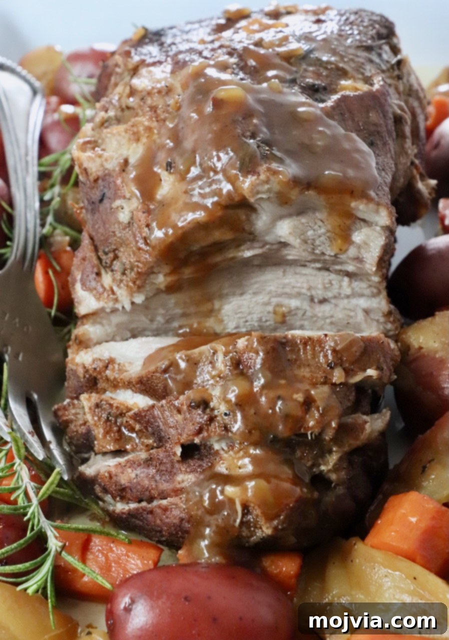 roasted pork on a serving platter with vegetables and rosemary