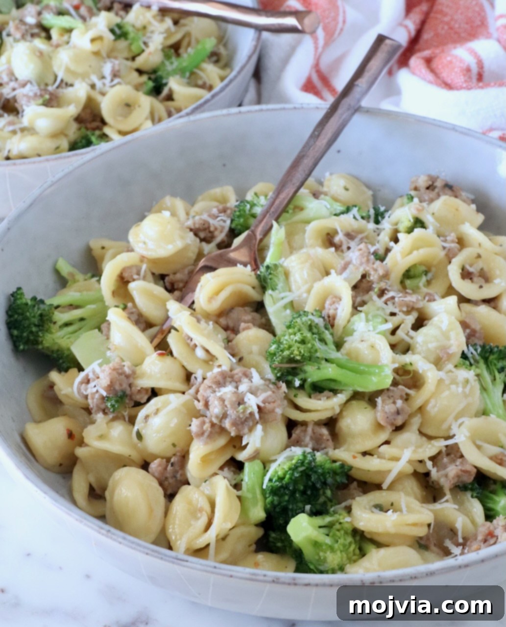 Savory Sausage and Broccoli Orecchiette 2 cooked orecchiette pasta with broccoli and cooked sausage in a bowl with a fork