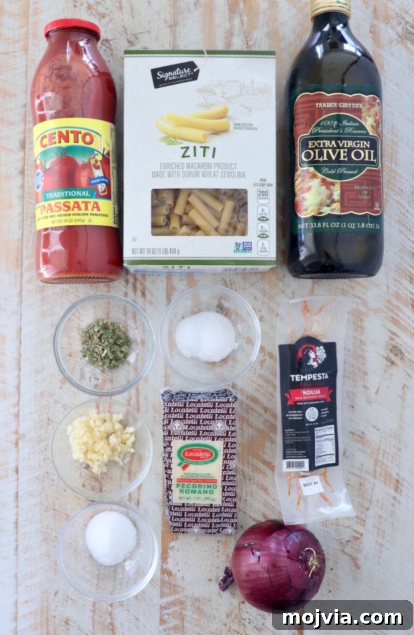 Fiery Nduja Tomato Sauce 3 A collection of fresh ingredients for tomato nduja sauce laid out on a white wooden board, including tomatoes, onions, garlic, nduja, and olive oil
