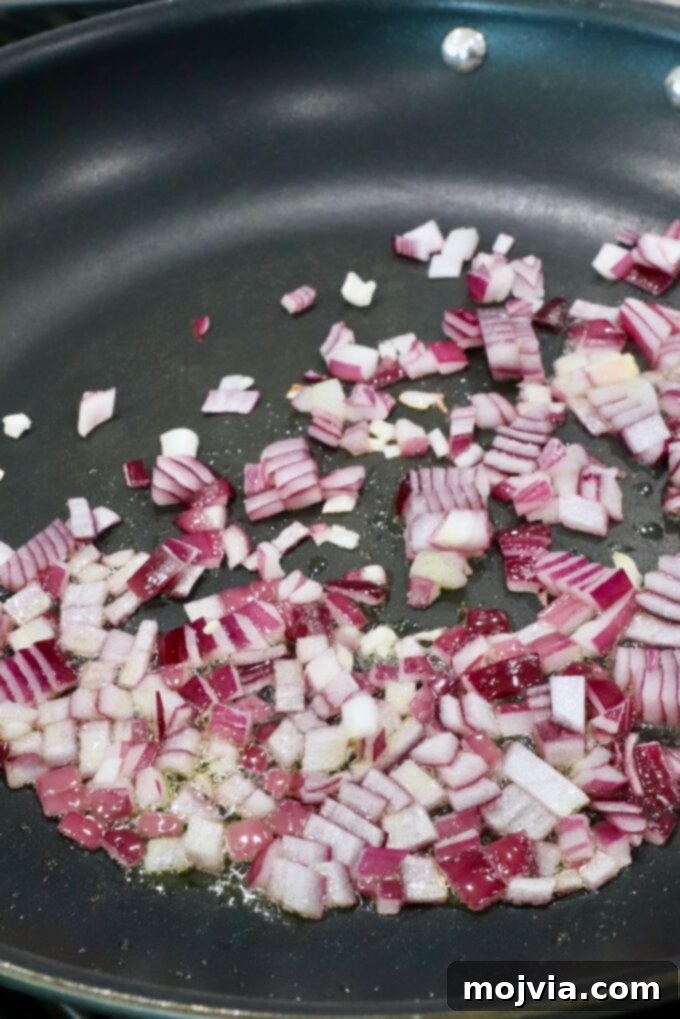 Fiery Nduja Tomato Sauce 4 Finely diced red onions gently sautéing in a skillet, creating a fragrant base for the sauce