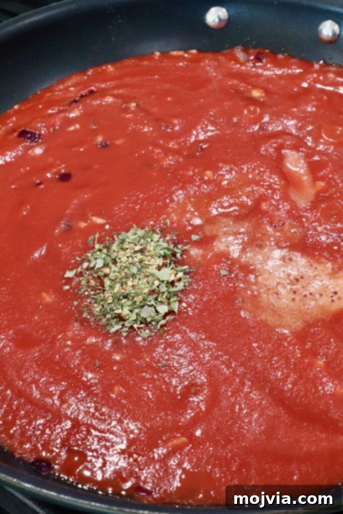 Fiery Nduja Tomato Sauce 5 Rich, seasoned tomato passata simmering in a skillet, absorbing flavors and thickening into a vibrant sauce