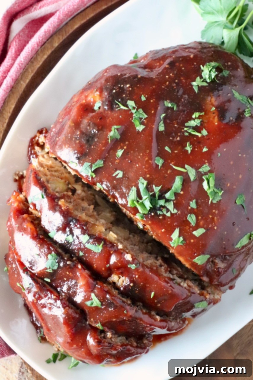 Perfect Air Fryer Meatloaf 12 partially sliced cooked and glazed meatloaf on a white plate
