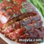 glazed, cooked meatloaf partially sliced on a plate